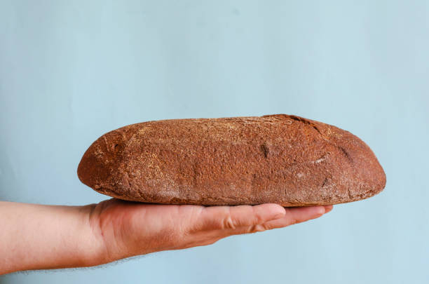 istock Loaf of rye bread lies on an open palm. 1275465374