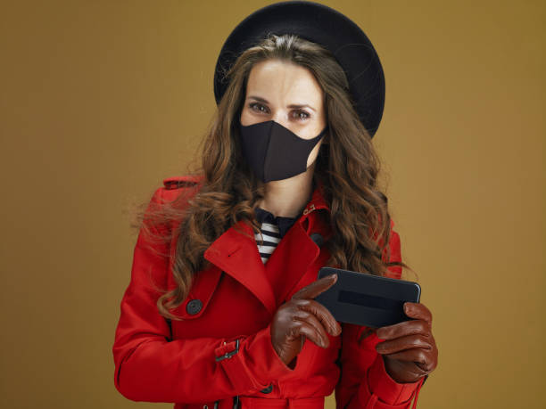 istock trendy woman using phone applications against brown background 1275465388