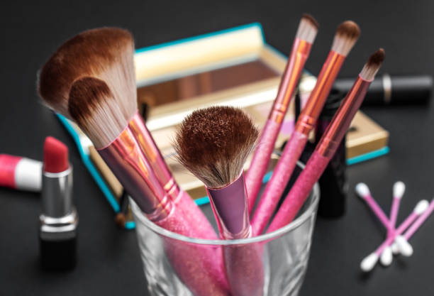 istock Professional makeup brushes with other cosmetics tools on black desk. 1275469667