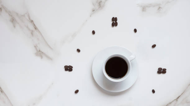 istock black coffee in white ceramic cup and coffee beans pattern in clock face forming on white marble tabletop 1275495349