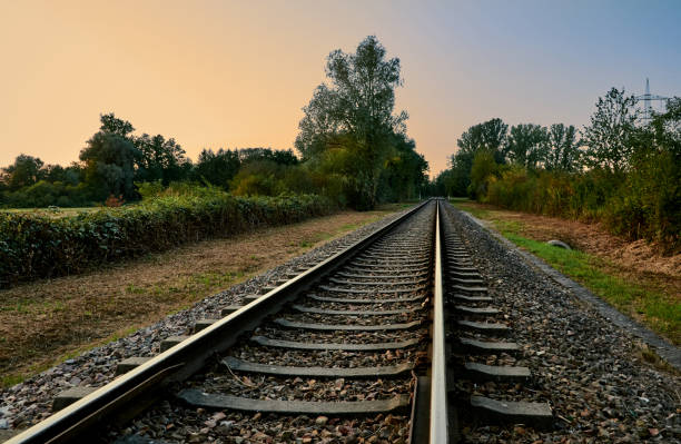 istock Railroad through countryside nature at sunset on a beautiful summer evening 1275496528