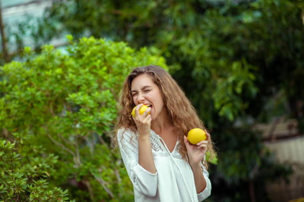 istock Woman in white holding two lemons in hands 1275504521