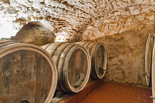 Wine wooden oak barrels closeup in the ancient cellar.