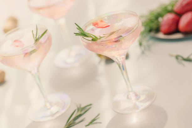 istock Summer drink with white sparkling wine. Homemade refreshing fruit cocktail or punch with champagne, strawberries, ice cubes and rosemary on light blue background. 1275544796