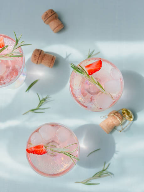 istock Summer drink with white sparkling wine. Homemade refreshing fruit cocktail or punch with champagne, strawberries, ice cubes and rosemary on light blue background. 1275545113