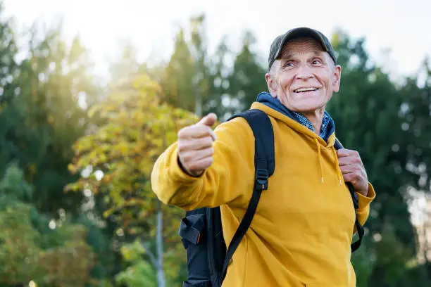old traveler man with smile on face wearing cap calling people to adventure in mountains forest background outdoor
