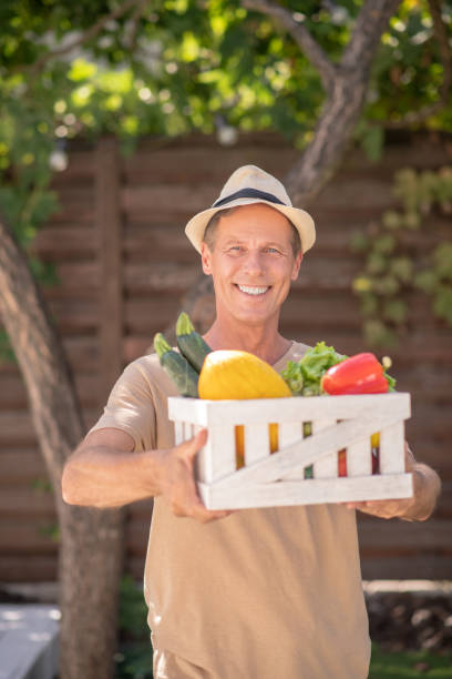 istock Happy male in straw hat holding basket with vegetables 1275575454