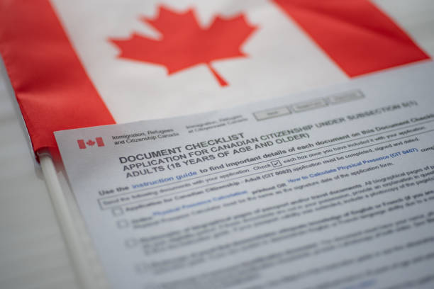 istock Document check list application for canadian citizenship next to Canadian flag, close up view. 1275584584
