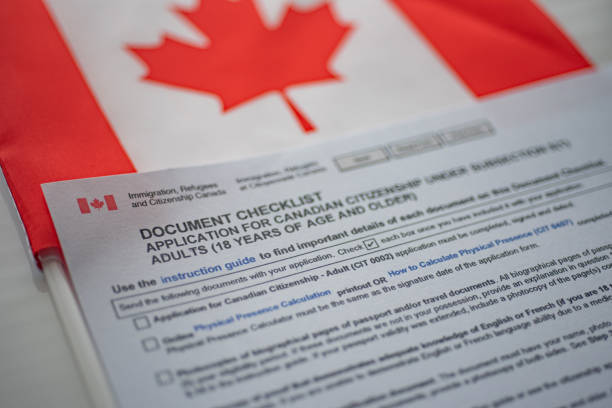 istock Document check list application for canadian citizenship next to Canadian flag, close up view. 1275587612