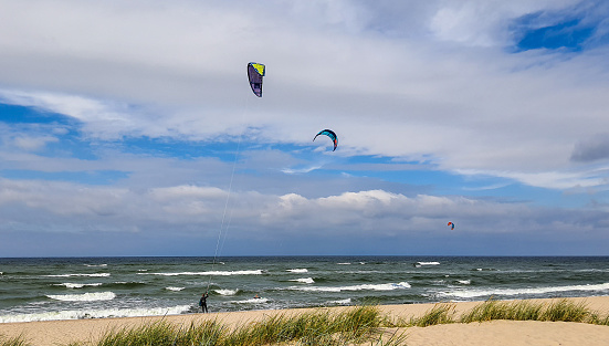 People go kitesurfing on the seaside on a cloudy day in stormy weather.