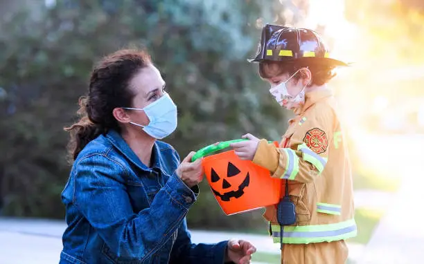 Photo of Mature woman and a child boy wearing protective face masks before going to ask trick or treat halloween