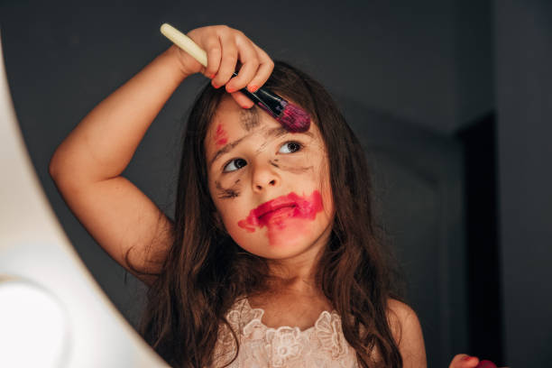 Cute little girl doing make up in front of mirror stock photo