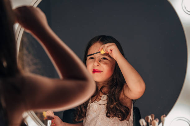 istock Cute little girl doing make up in front of mirror 1275675644