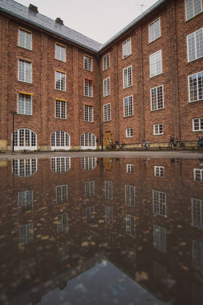 Large industrial red brick house, with visible reflection on the ground in a pool of water. Autumn cold setting, good for background