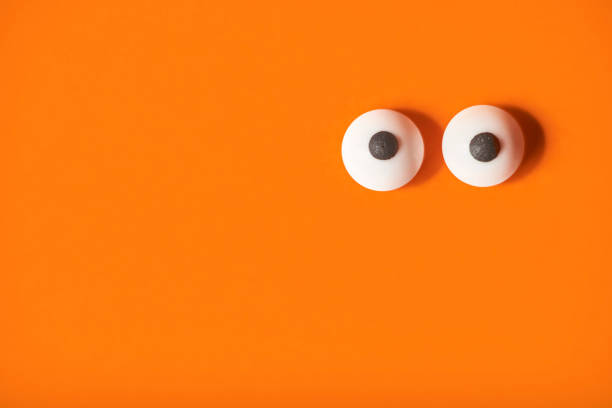 istock Halloween background, pair of eyes on orange, copy space. 1275677073