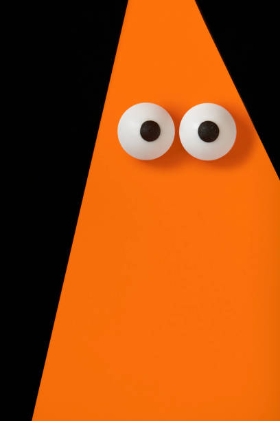 Halloween background, Orange ghost with bulging eyes on black, copy space.