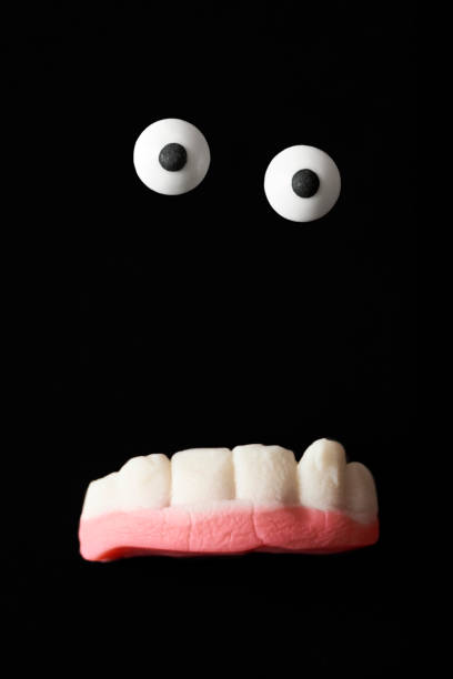 Funny creature, halloween monster, sugar eyes and gummy teeth on a black background Funny creature, halloween monster, sugar eyes and gummy teeth on a black background eye candy stock pictures, royalty-free photos & images