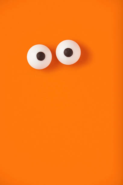 Halloween background, pair of eyes on orange, copy space.