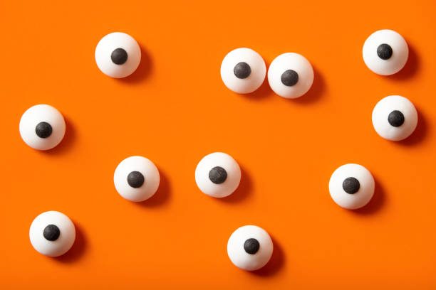 istock Halloween background, many white bulged eyes on orange background 1275677130
