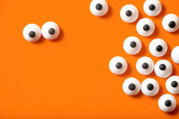 istock Halloween background, many white bulged eyes on orange background, copy space. 1275677131