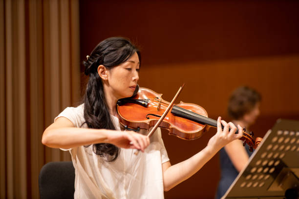 istock Woman playing violin with piano at classical concert 1275677143