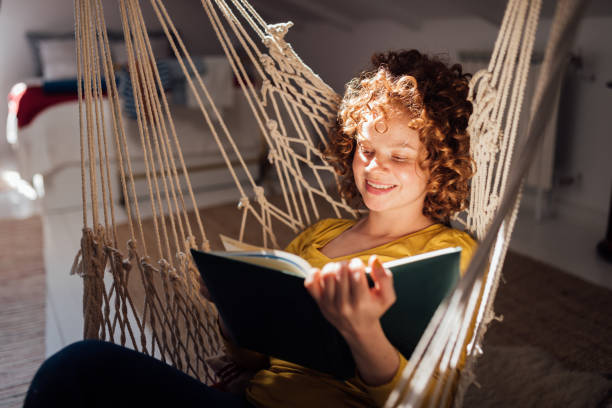 istock Cheerful young Caucasian redhead woman reading a book 1275677702