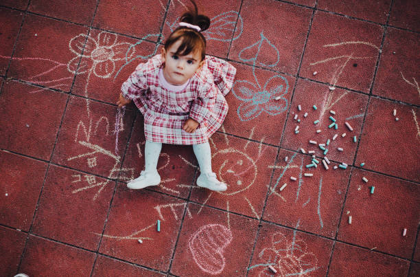 istock Adorable little girl drawing with colorful chalks on asphalt 1275682032