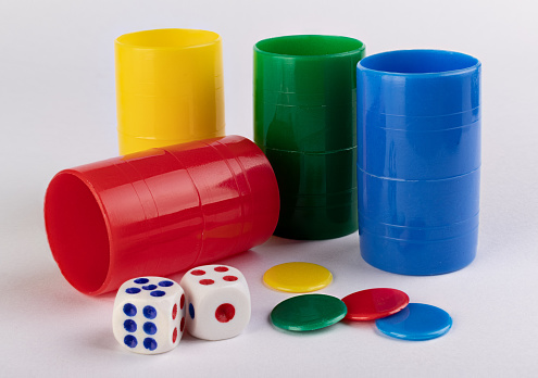 Used dices, tokens and color shaking cups on a white surface