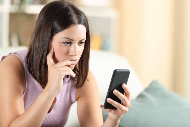 istock Pensive woman checking smart phone content at home 1275683501