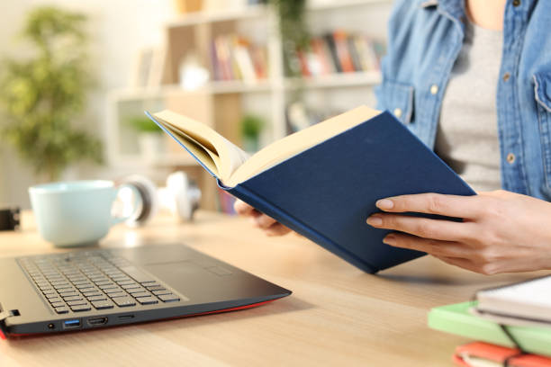 istock Student hand reading book sitting a desk at home 1275685635