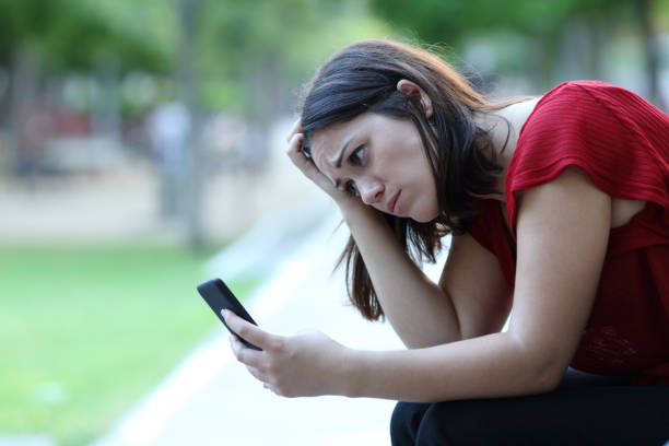 istock Sad woman in a park checking phone 1275685724