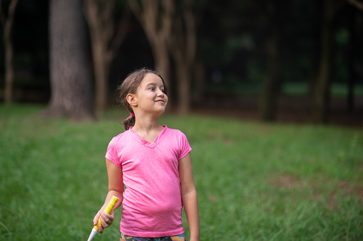 Little girl playing badminton in public park