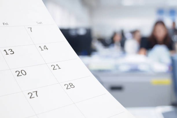 istock Close up white paper desk calendar on table with blurred office interior background 1275708025