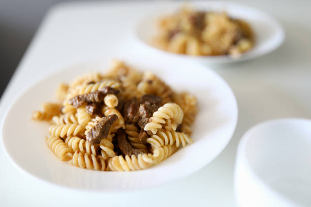 Close-up of traditional italian pasta bolognese served on white plate. Delicious meal for dinner. Portion for two people. Healthy and yummy food concept