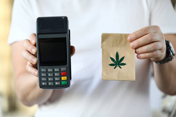 Electronic device with knobs Close-up of courier holding paper package with traditional meds. Cannabis in bag with leaf symbol. Cashier machine for fast payment. Nfc technology counter and remedy concept cannabis store photos stock pictures, royalty-free photos & images