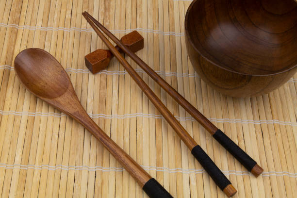 istock Wooden chopsticks and spoon with bowl on bamboo mat 1275712531