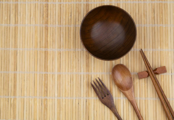 istock Wooden chopsticks, fork, spoon and bowl on bamboo mat with copy space 1275712568