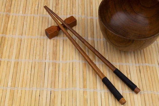 istock Wooden chopsticks and bowl on bamboo mat 1275712582