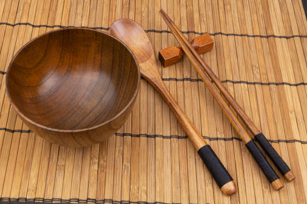 istock Wooden chopsticks, spoon and bowl on bamboo mat 1275712635