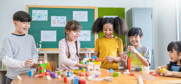 retrato de niños caucásicos asiáticos jugando bloques de colores en el aula. aprender jugando al concepto de estudio de grupo educativo. alumnos internacionales que realizan actividades de formación cerebral en la escuela primaria. - custom built fotografías e imágenes de stock