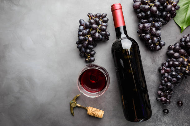 Red wine and ripe grapes Red wine in a glass and ripe grapes on gray background, top view merlot grape photos stock pictures, royalty-free photos & images