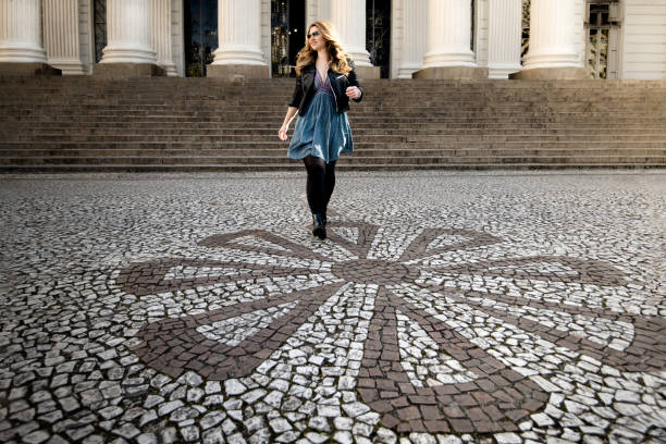 Young woman, walking in front of the steps of the Federal University of Paraná, at Praça Santos Andrade in Curitiba, Paraná, Brazil.