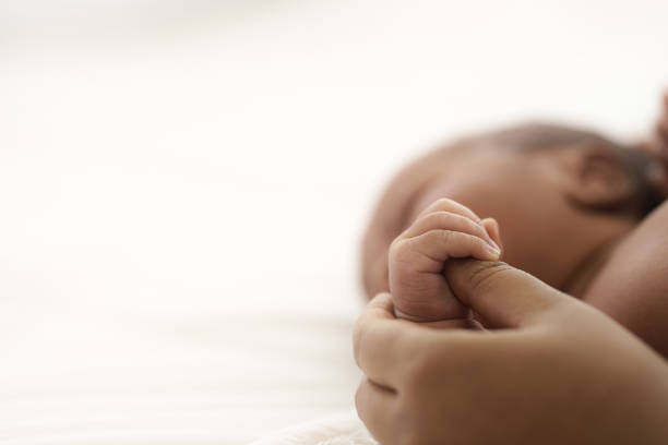 african american baby liegend auf dem bett, während mutter hände ziehen baby nach oben - baby blanket stock-fotos und bilder