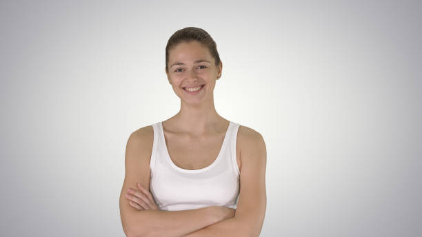 istock Smiling sports woman walking with arms folded on gradient backgr 1275734734