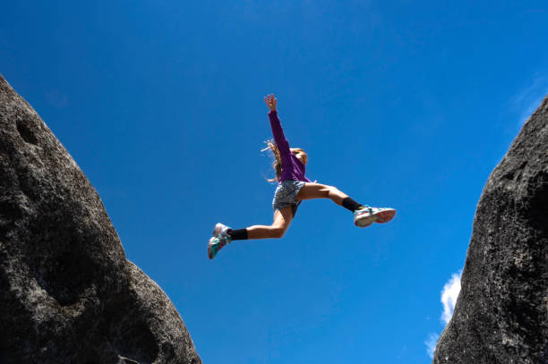 Family Hiking through Mountain Track Summer A mother, and her children trekking a mountain track on a summers day, jumping over rocks. leap of faith stock pictures, royalty-free photos & images