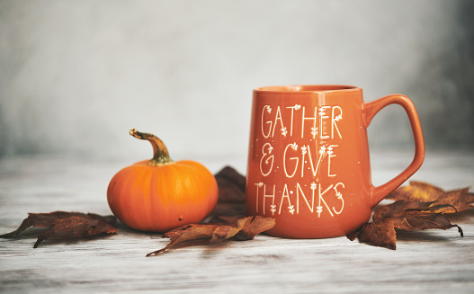 Fall background with pumpkin and coffee mug on white wood