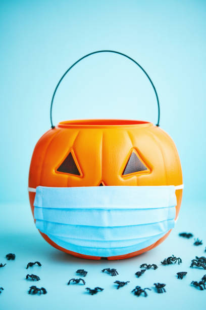 istock Halloween background with spiders and Jack O'Lantern bucket wearing face mask 1275748378