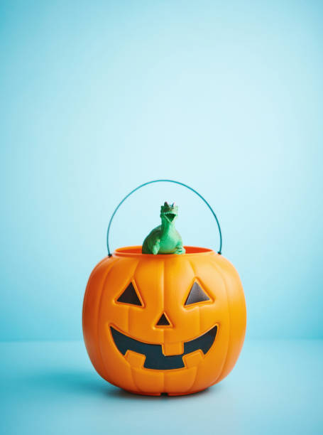 istock Halloween background with Jack O'Lantern bucket with dinosaur inside 1275748402