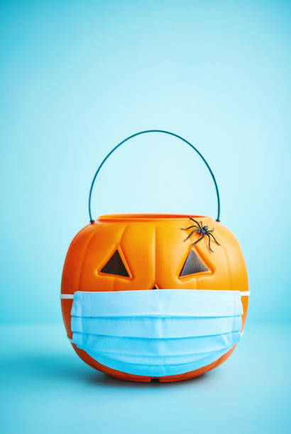 istock Halloween background with spiders and Jack O'Lantern bucket wearing face mask 1275748406