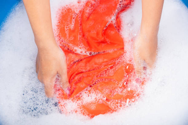 istock Woman use hands washing color clothes in basin 1275753374